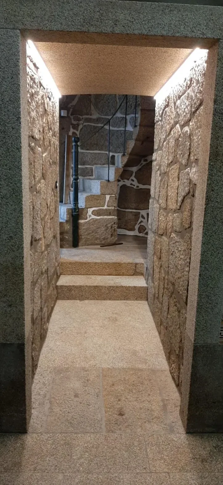 Passagem em granito com fitas LED escondidas ao longo do teto e escadas ao fundo