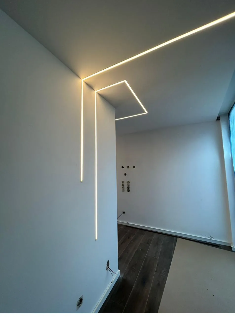 Sala com perfis LED embutidos no teto e na parede